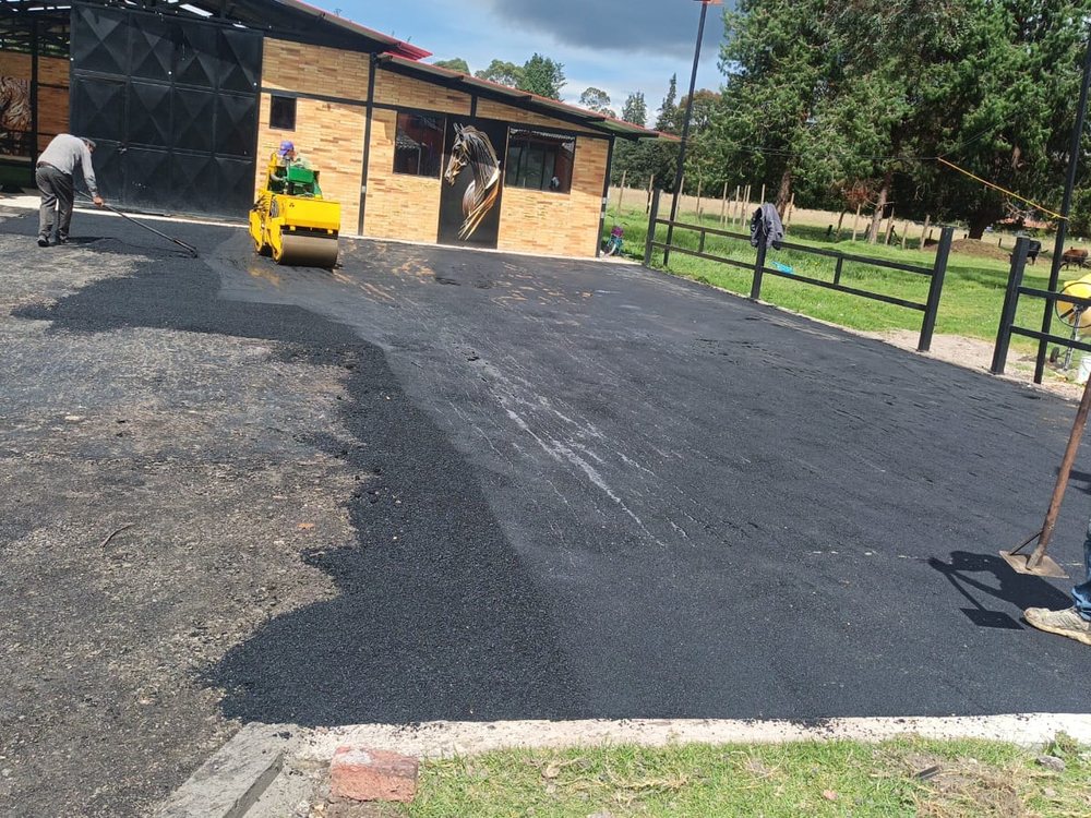 Cuadrilla y compactadora tendiendo mezcla asfáltica